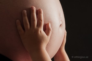Sonen håller om den gravid magen, en vacker gravidbild