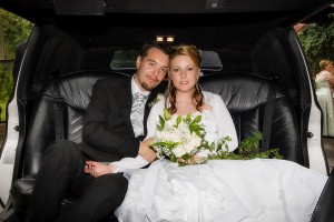 Brudparet poserar för bröllopsfoto i limousinen